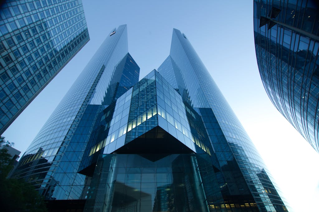 Low-angle view of modern glass skyscrapers reflecting a clear blue sky. Perfect for urban and architectural themes.